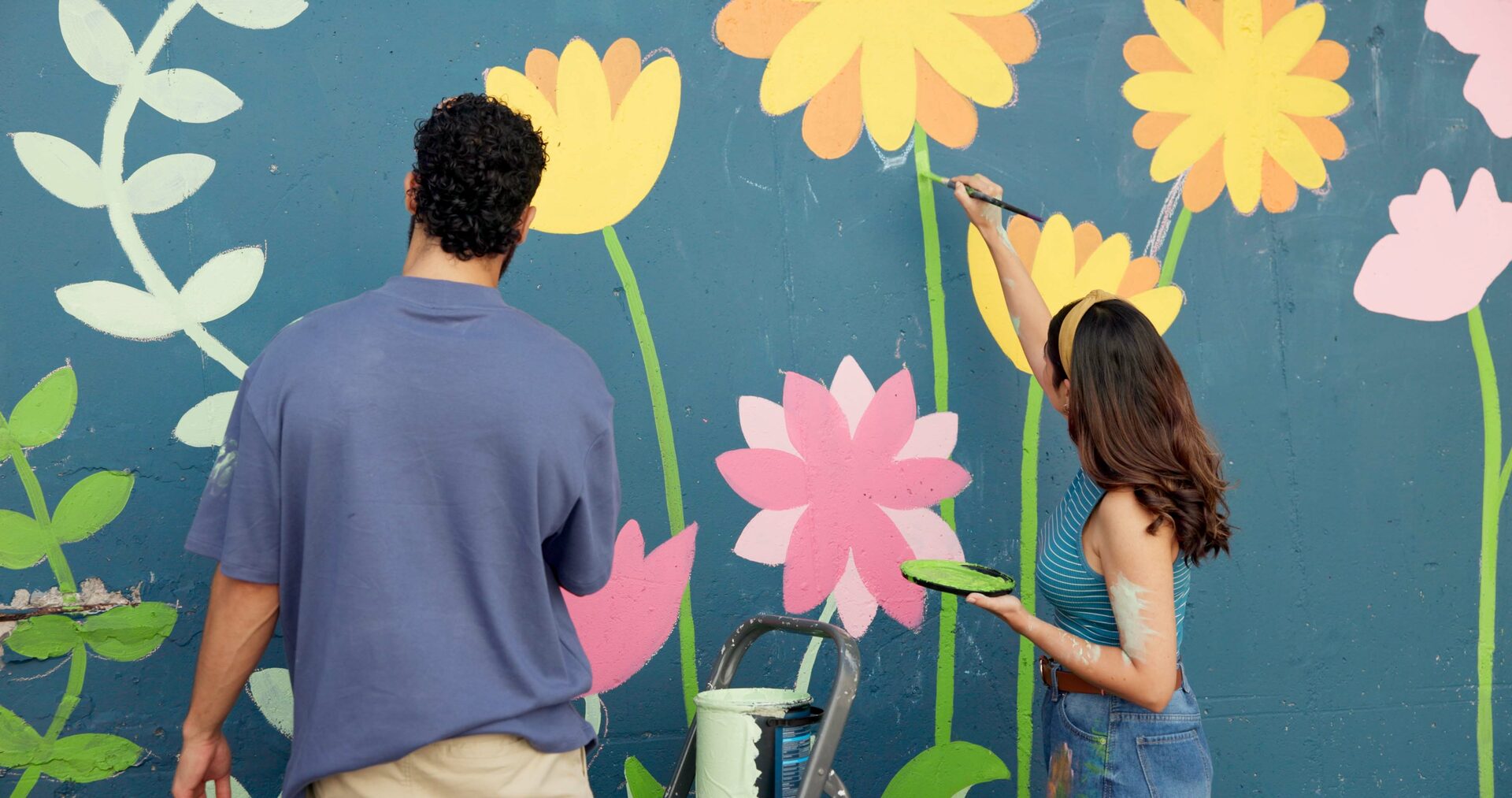 Hero image: two volunteers painting a flower mural on a community wall